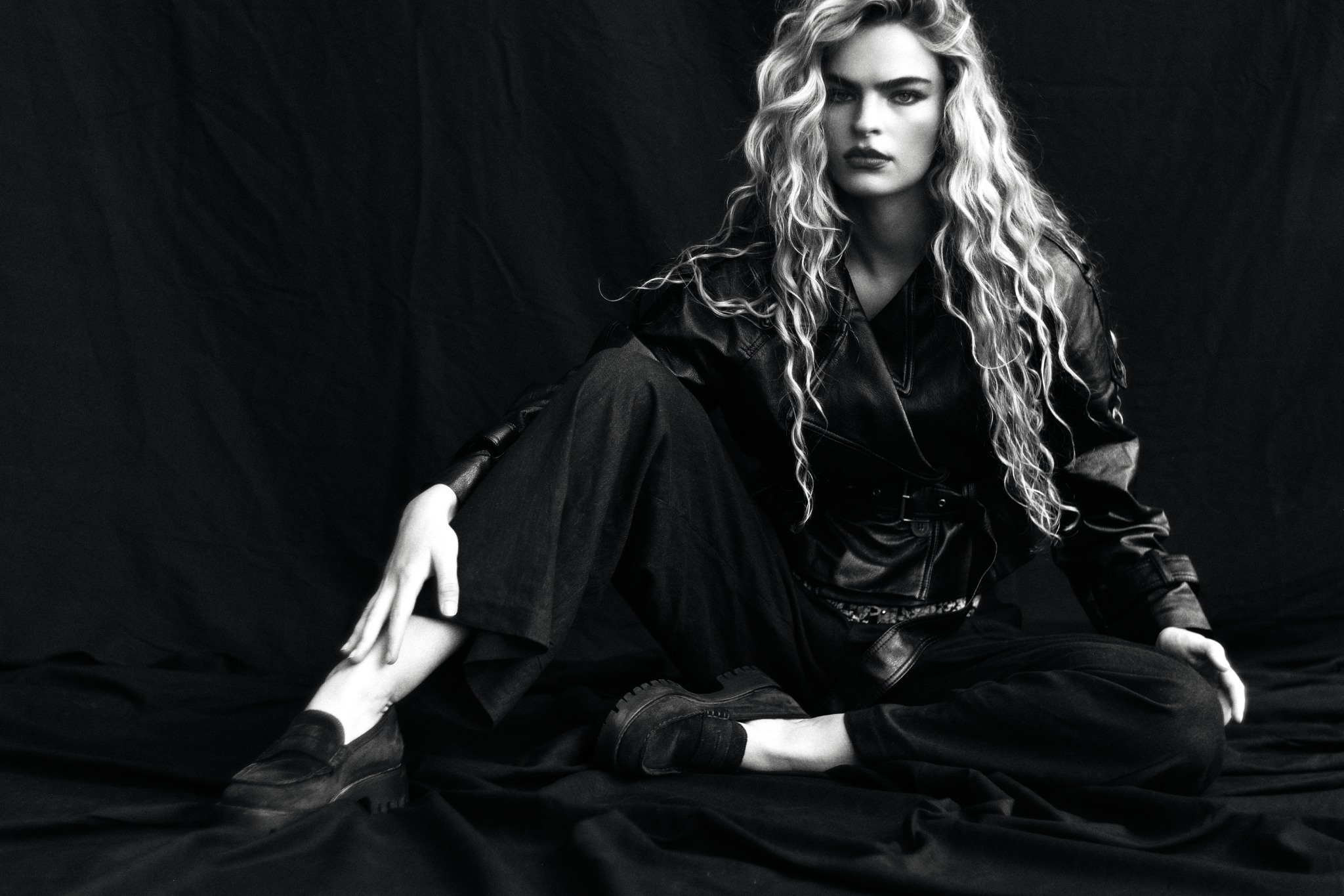 Seated fashion editorial in flowing black fabric