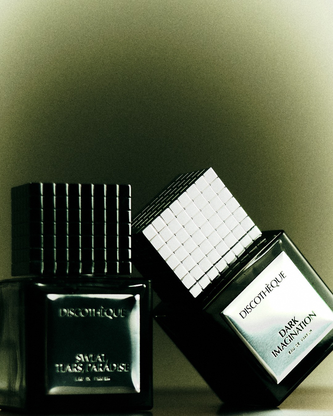 Two perfume bottles in green-toned light