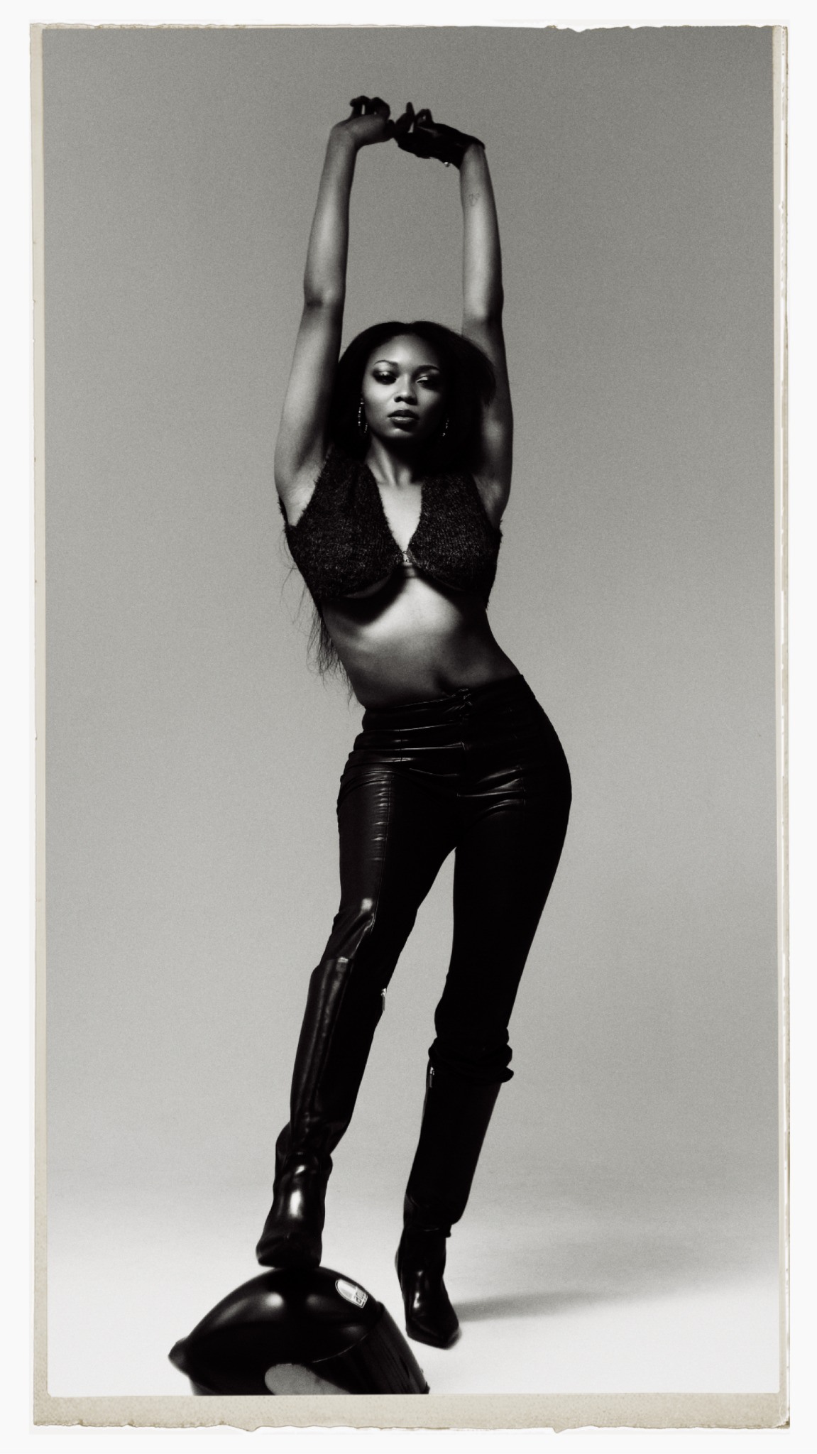 Studio editorial in a black bodysuit and tall boots