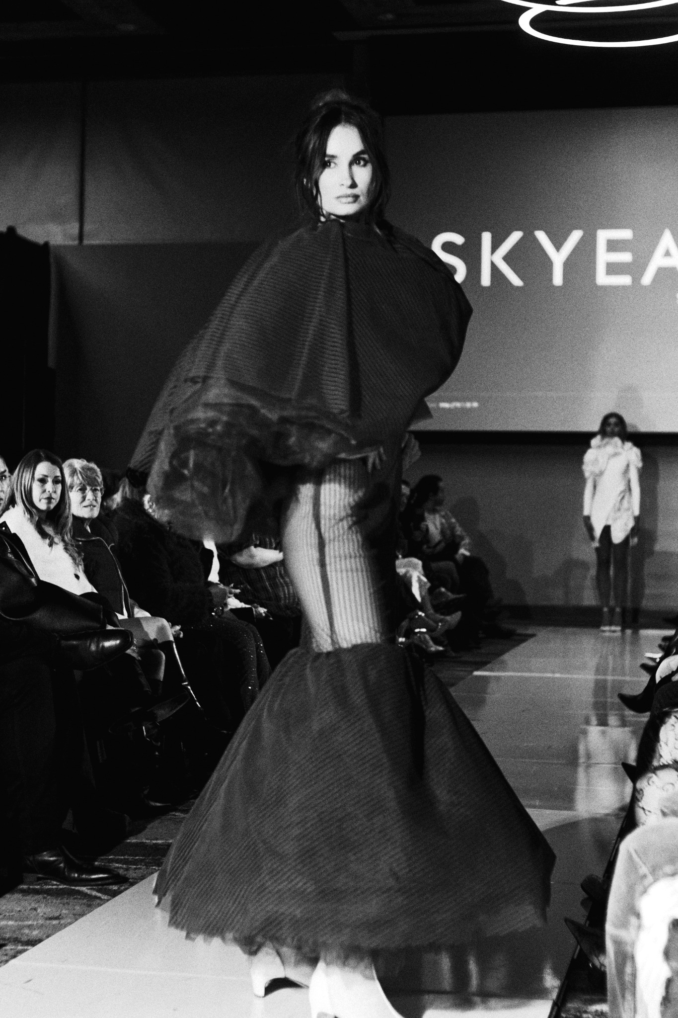 Runway model in a dark sculptural dress