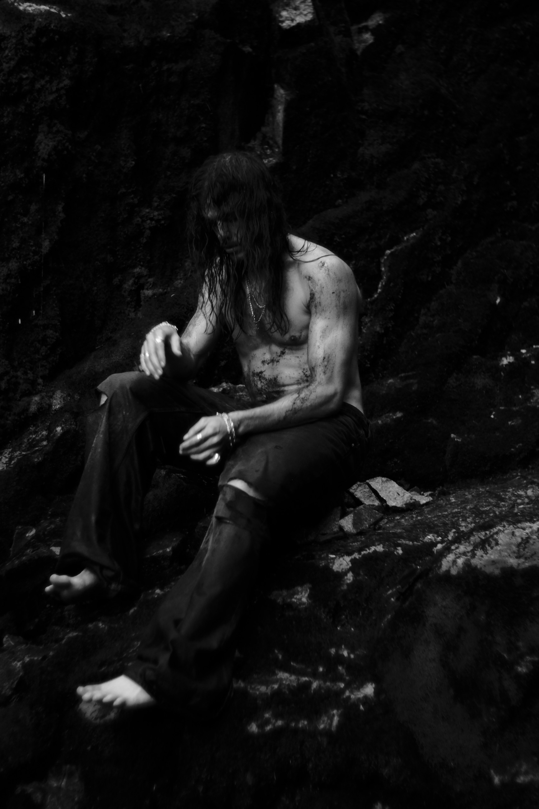 Monochrome seated portrait among dark rocks