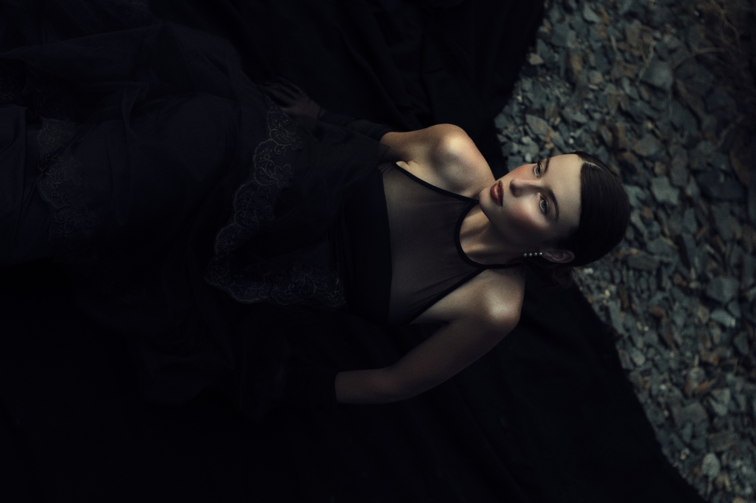 Reclining editorial in black lace on stone
