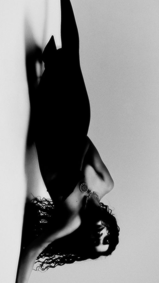 Model in black arching backward against white with hair falling, high-contrast black and white