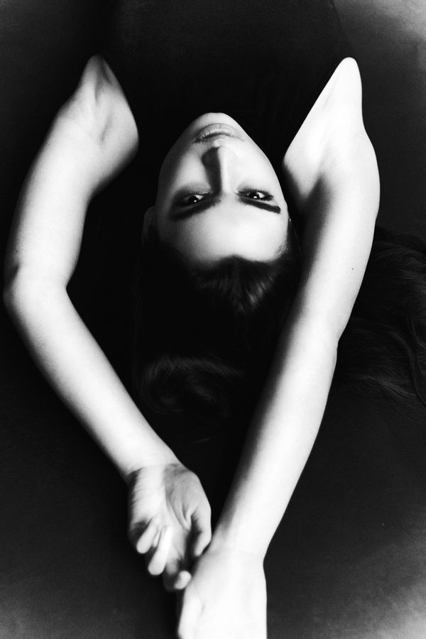 Woman lying back with her arms crossed above her head, photographed from above in black and white