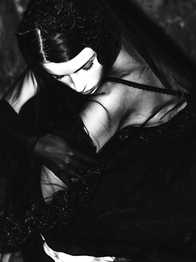 Woman with her head wrapped in sheer black fabric and dark lipstick, dramatic black and white portrait